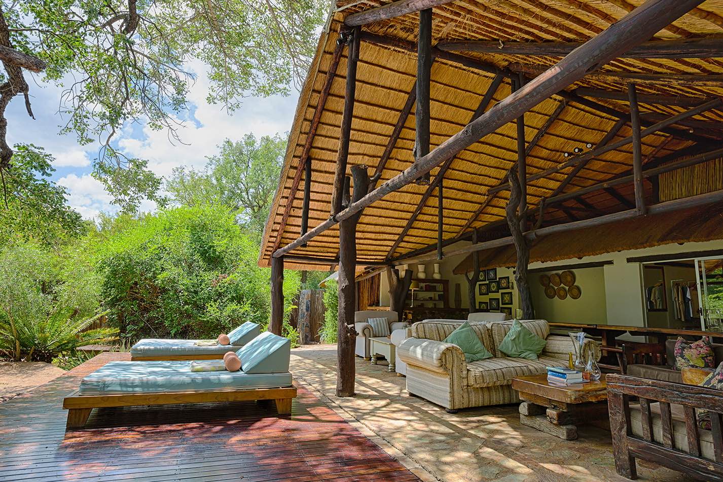 A deck designed for relaxation with sun loungers under the trees at Chapungu Tented Camp