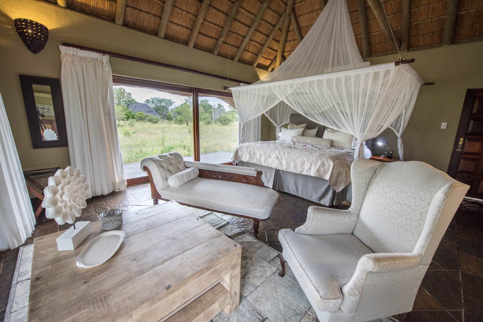 Kambaku River Sands guest bedroom with high thatch ceilings and wide glass windows