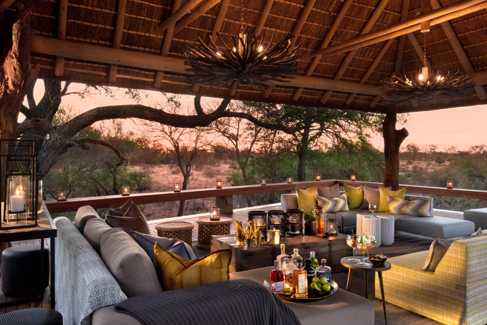 Lounge under thatch on a wooden deck with a view onto the surrounding bush