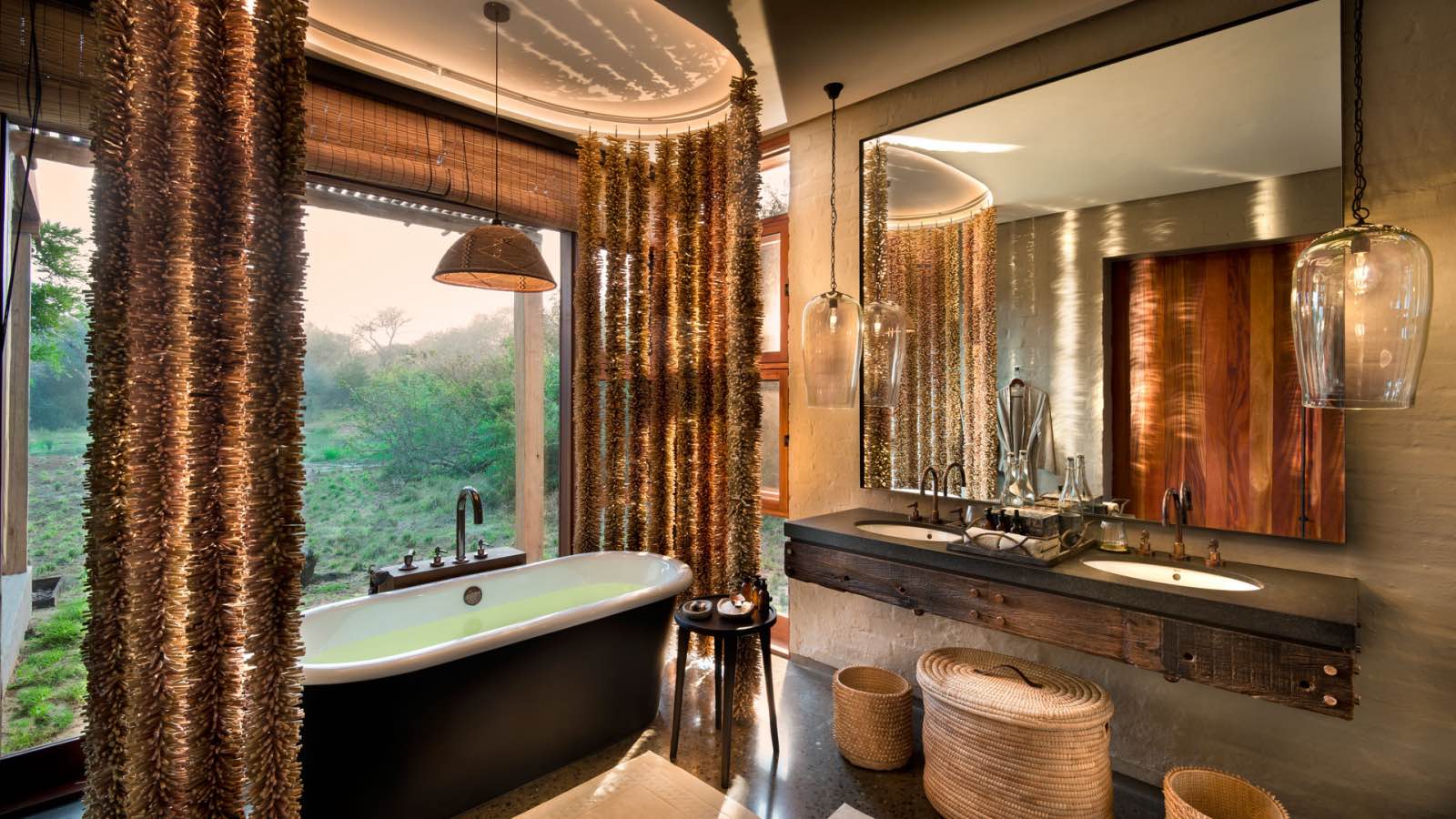 A bathtub with a view through big glass windows at Phinda Homestead