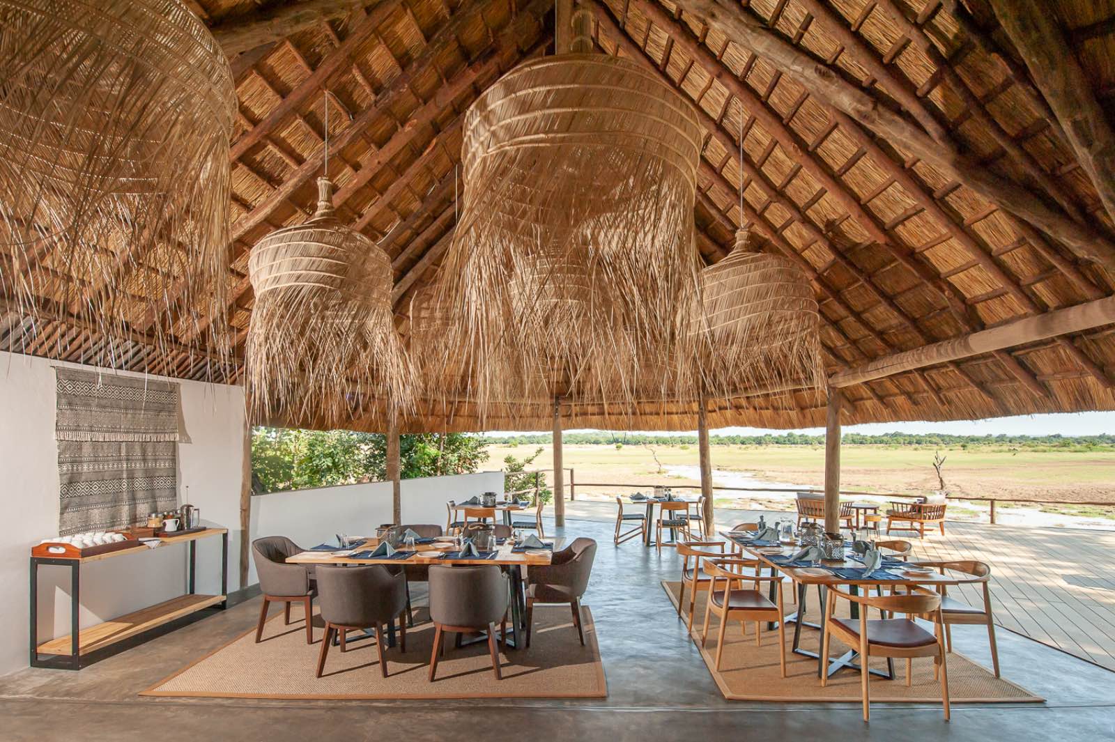 A dining area under thatch with soft furnishings and African accents