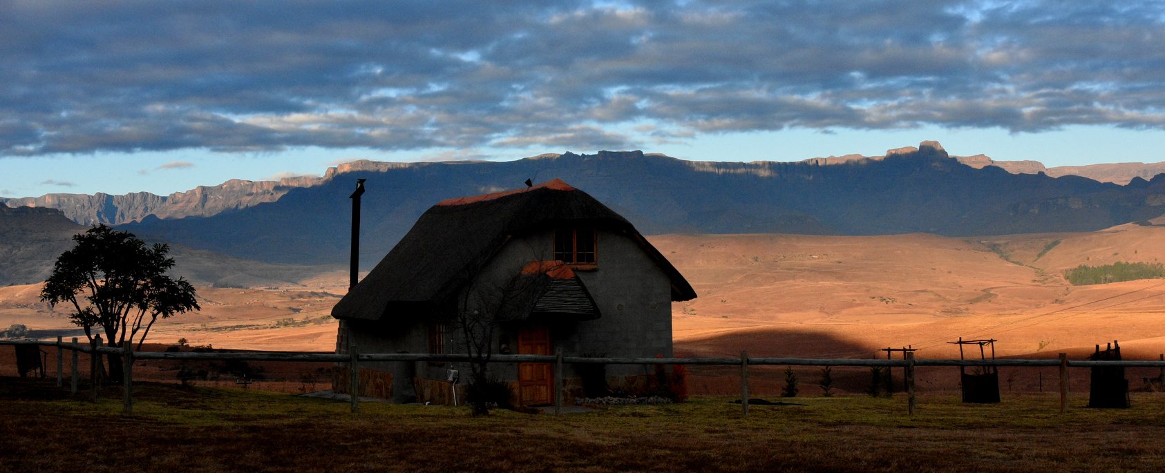 Rustic cottages at Berghouse with a backdrop of the Drakensberg