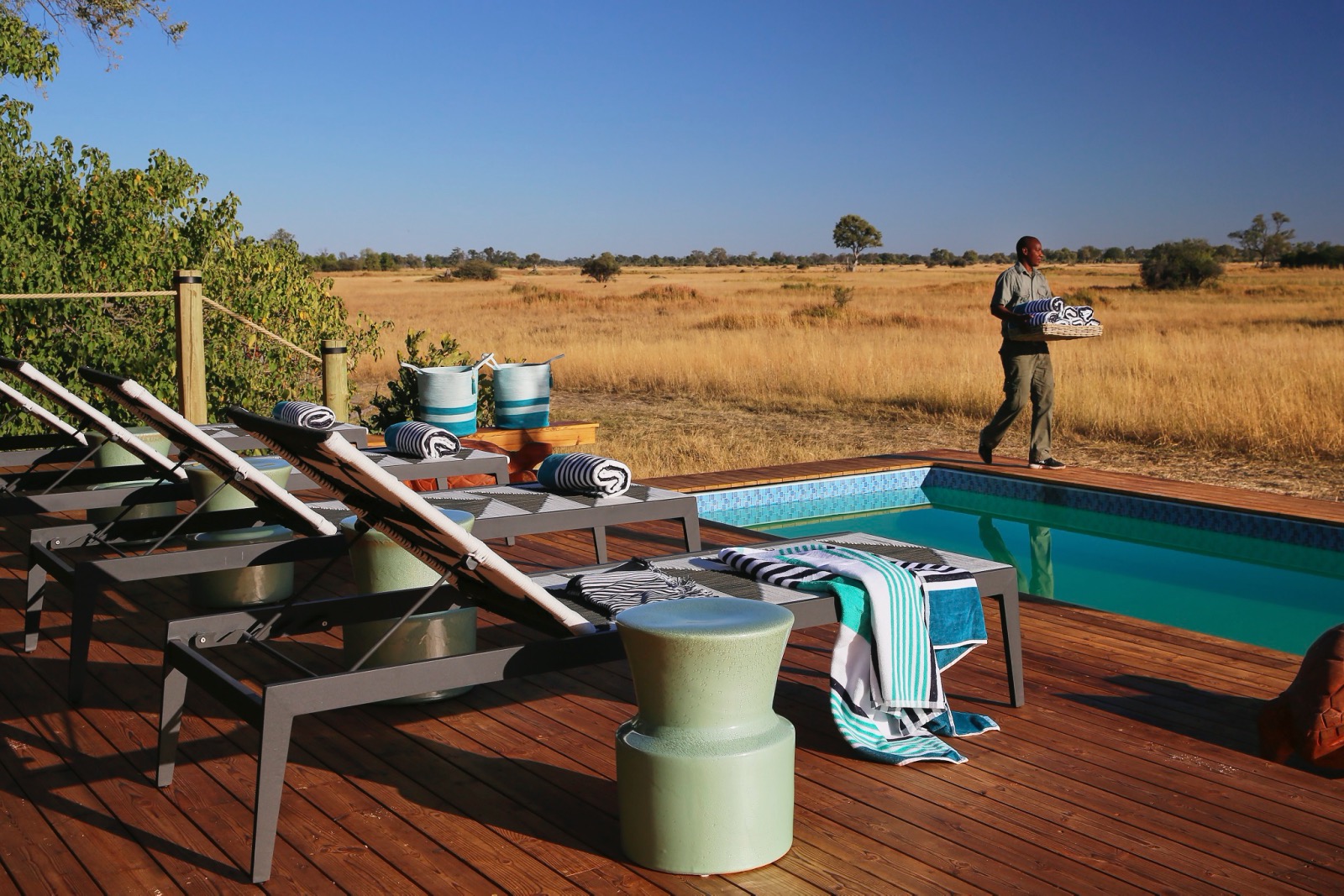 A refreshing swimming pool and relaxing sun loungers in the wide, open savanna at Tuludi Camp in Botswana
