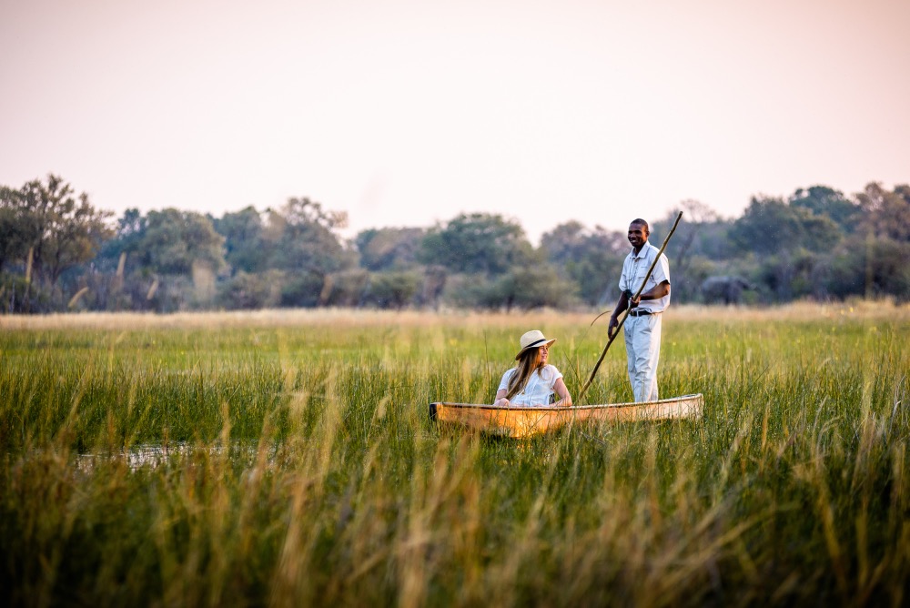 Solo traveller on a traditional canoe with guide in Botswana wetland